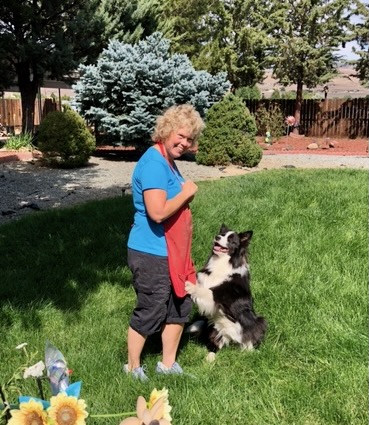 Dale smiles at her dog while standing together on the lawn in her backyard.
